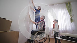 Young happy family happy father and disabled person in wheelchair with wife and joyful son are choosing new wallpaper in