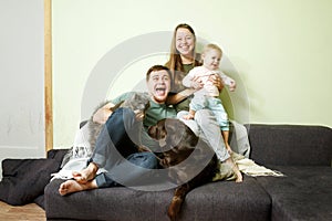 Young happy family with little toddler kid and pets dog and cat at home on the couch