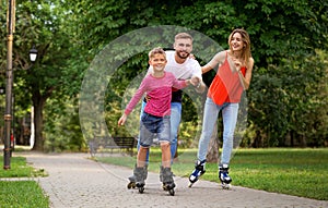 Young happy family roller skating in park