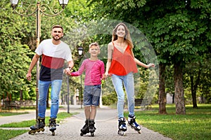 Young happy family roller skating in park