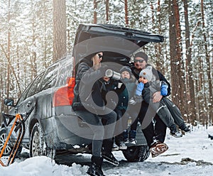 Young and happy family spending their time together in winter wood