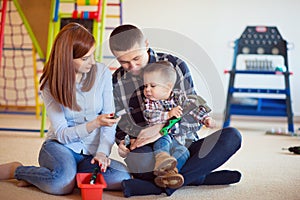 Young happy family with toddler boy playing together at home