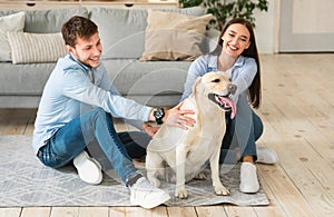 Young happy family of two sitting on floor with dog