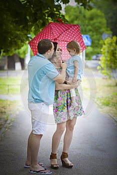 Young happy family under umbrella