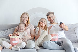 young happy family watching movie on couch