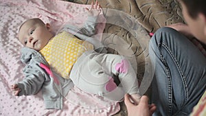 Young happy father dress his little daughter on sofa in bedroom