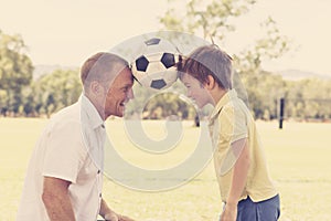 Young happy father and excited 7 or 8 years old son playing together soccer football on city park garden posing sweet and loving h