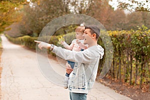 Young happy father having time with his little daughter outdoor and pointing at something