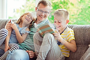 Young happy father reading book with cute children at home