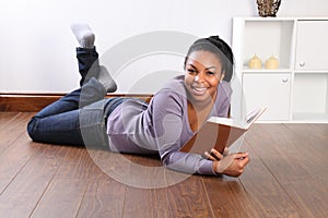 Young happy female student reading book at home