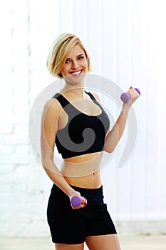 Young happy fit woman with dumbbells