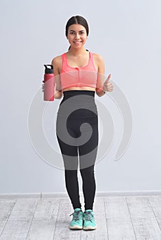 Young happy fitness girl with sporty body drink water at studio on a white background. Beautiful fit Girl
