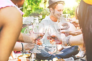 Young happy friends cheering and having fun together in a picnic at backyard - Group of people toasting with red wine glasses