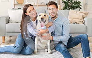 Young happy friends with dog sitting in living room