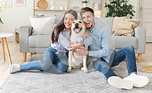 Young happy friends with dog sitting in living room