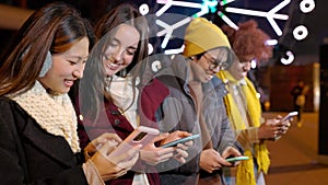 Young happy friends having fun together using cell phones on city street