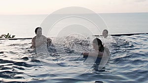 Young happy friends having fun in the view pool at sunset. Splashing water in the pool. Happy people on vacation. Traveling with