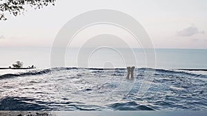 Young happy friends having fun in the view pool at sunset. Splashing water in the pool. Happy people on vacation. Traveling with