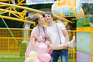 Young happy funny couple in love walks and has fun in an amusement park