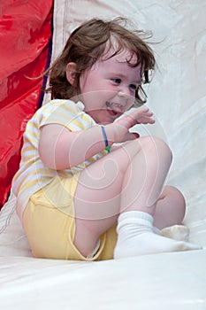 Young happy girl child riding inflatable slide outdoors on a warm summer day.