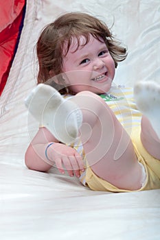 Young happy girl child riding inflatable slide outdoors on a warm summer day.