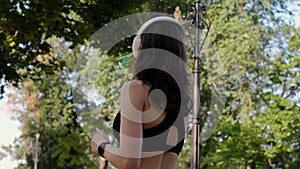 Young happy girl doing yoga in the park, listening to music with headphones, sitting in lotus position