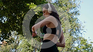 Young happy girl doing yoga in the park, listening to music with headphones, sitting in lotus position