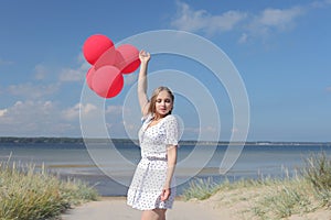 Young happy girl in dress with red balloons photo