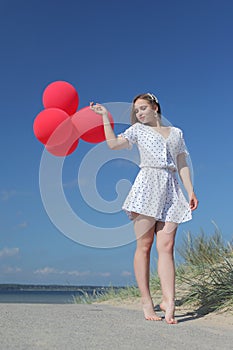 Young happy girl in dress with red balloons photo