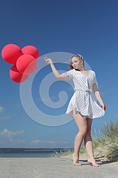 Young happy girl in dress with red balloons photo