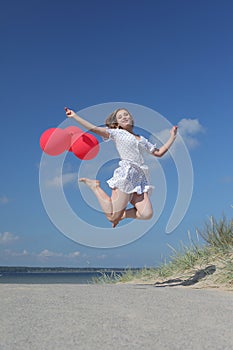 Young happy girl in dress with red balloons photo