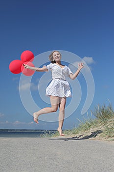 Young happy girl in dress with red balloons photo