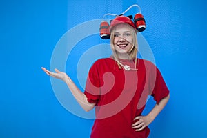 Young happy girl fan holds a place for text with his hand and smiles, cheerleader on a blue background