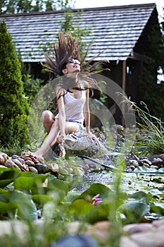 Young happy girl with garden streamlet near pond