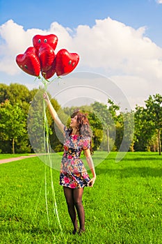 Young happy girl have fun with red balloons outdoor