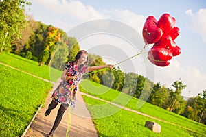 Young happy girl have fun with red balloons outside