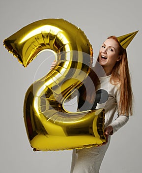 Young happy girl with huge gold digit balloon as a present for birthday party