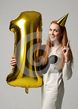 Young happy girl with huge gold digit one balloon as a present for birthday party