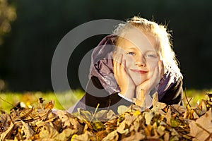 Young happy girl lying on floor in autumn leaves