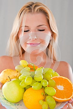 Young happy girl with a plate of juicy fruits