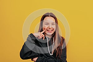 Young happy girl pointing to her clean face without makeup. Dimples.