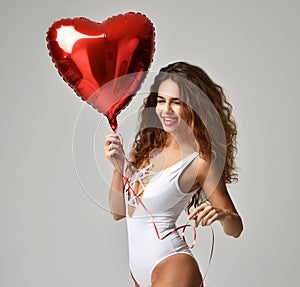 Young happy girl with red heart balloon as a present for birthday party smiling