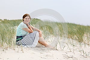 Young happy girl relaxing on sand dunes of the beach of St.Peter Ording