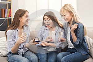 Young happy girl showing her proposal ring to surprised girlfriends