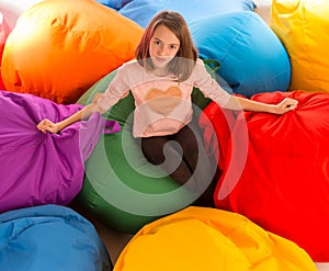 Young happy girl sitting between beanbag chairs