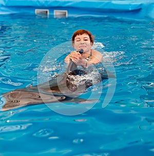 Young happy girl swimming with dolphin
