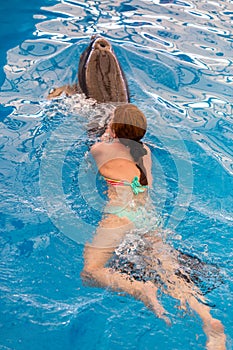 Young happy girl swimming with dolphin