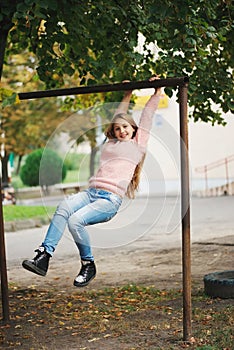 Young happy girl swinging on the crossbar