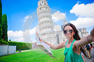 Young happy girl taking selfie background famous Pisa Tower. Tourist traveling visiting The Leaning Tower of Pisa.