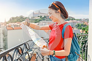 Happy girl traveler looks at the map and tries to find the right direction for the next attraction in the European city